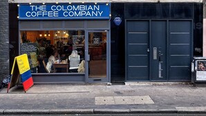 Un bâtiment sur lequel on peut lire l’inscription « The Colombian Coffee Company », et dont la devanture est ornée d’une grande vitrine.