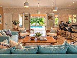 A spacious living area with a pool view, a kitchen with bar seating, and a cozy seating arrangement.