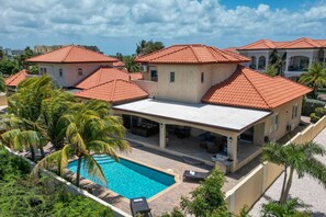 A residential complex with multiple houses, a swimming pool, and palm trees.
