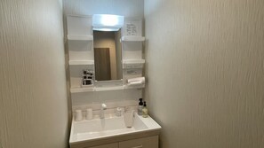 A bathroom with a white sink, mirror, and shelves with toiletries. - WHITE HOTEL GRAND HAKUBA (Omachi)