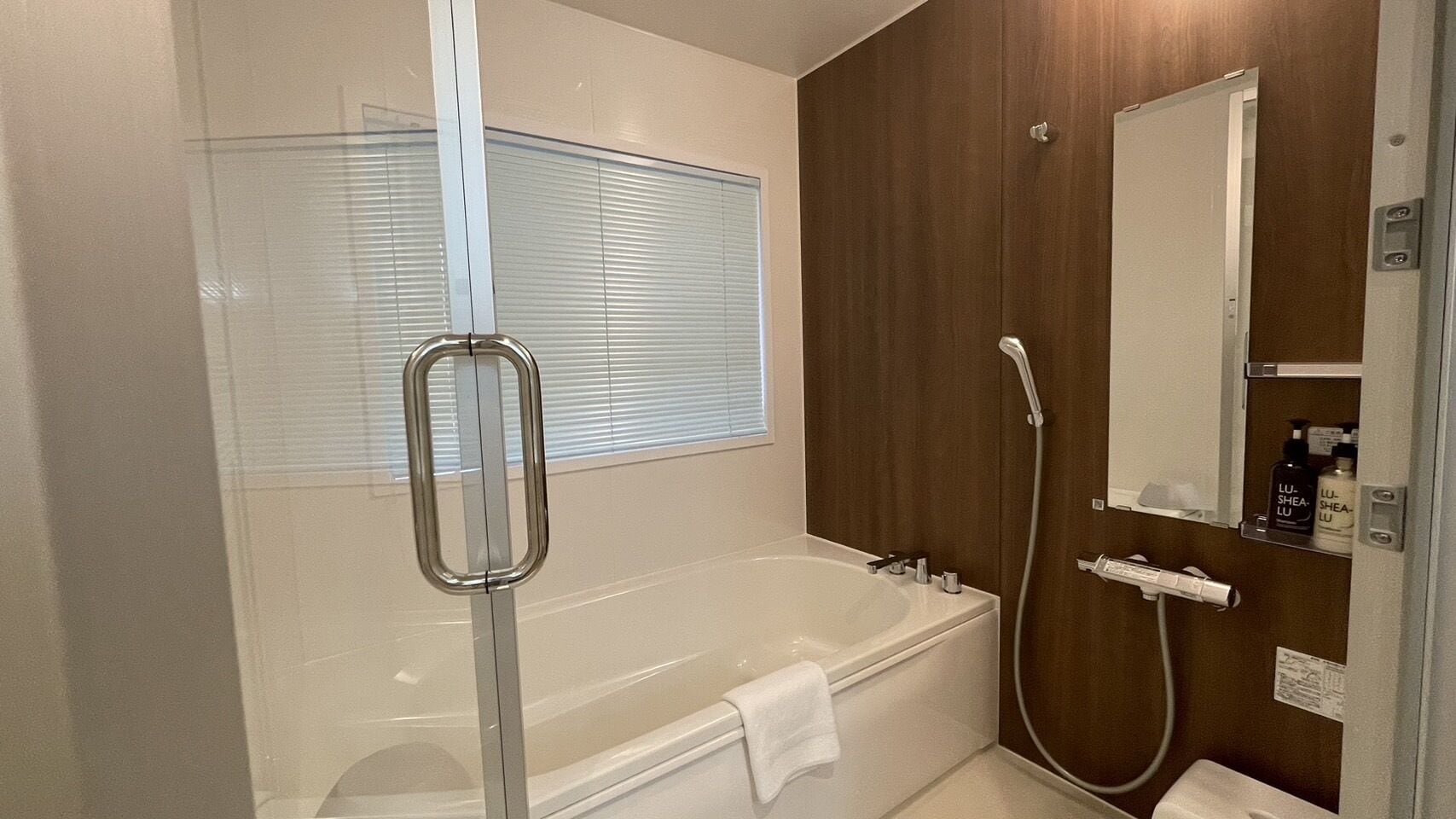 A modern bathroom with a bathtub, a shower, and a mirror.