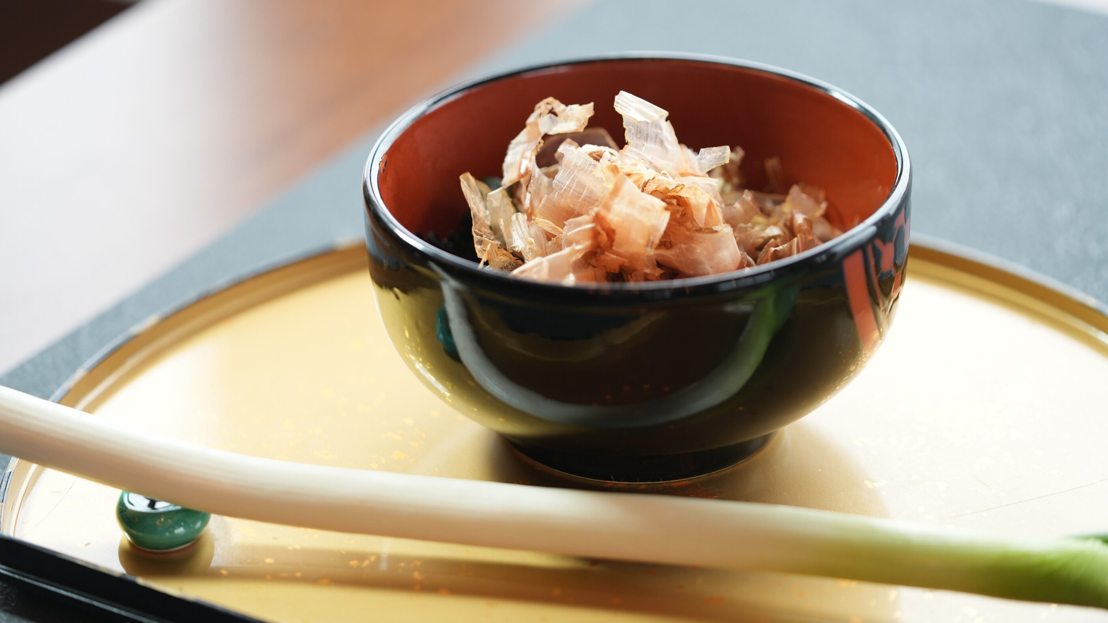 A bowl of food with chopsticks on a tray.
