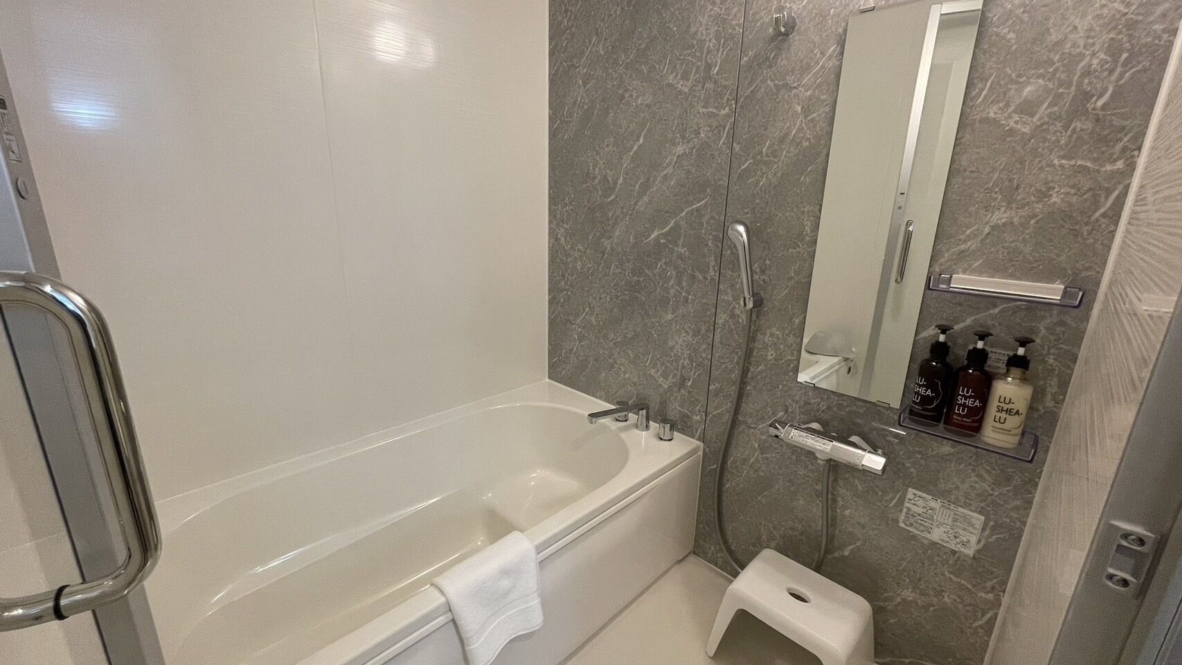 A modern bathroom with a bathtub, a shower, a toilet, and a small step stool.