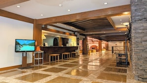A spacious lobby with a checkered floor, wooden beams, a reception desk, and a television displaying a scenic view. - WHITE HOTEL GRAND HAKUBA (Omachi)