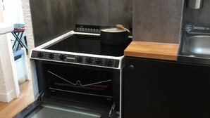 Una cocina con horno empotrado, escurreplatos y encimera de madera.