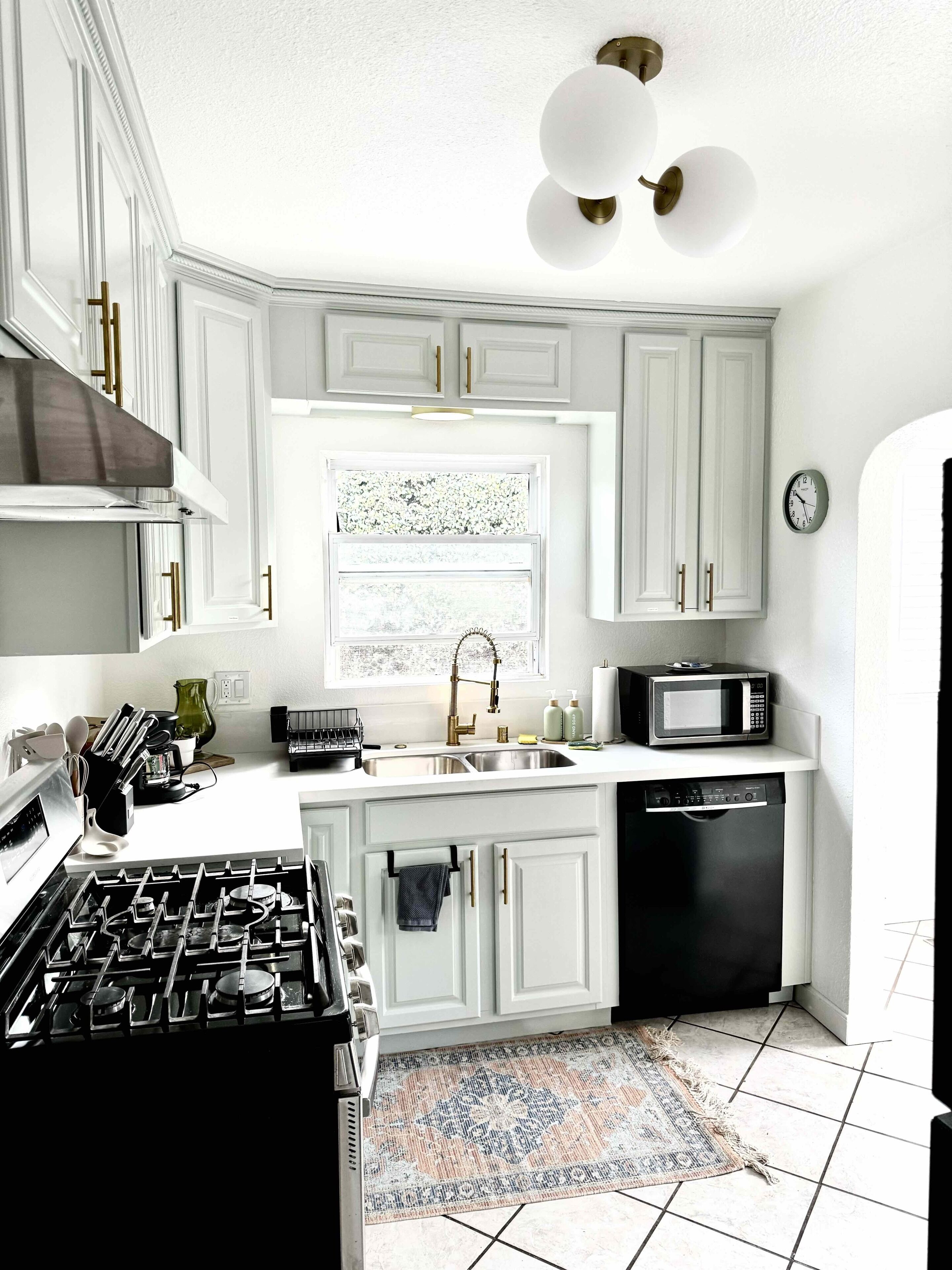 A modern kitchen with white cabinetry, a gas stove, a microwave, and a dishwasher.