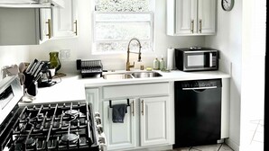 Una cocina moderna con armarios blancos, estufa a gas, microondas y lavavajillas.