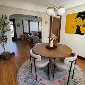 Un coin repas comprenant une table ronde, quatre chaises, un vase avec des fleurs et un tapis.