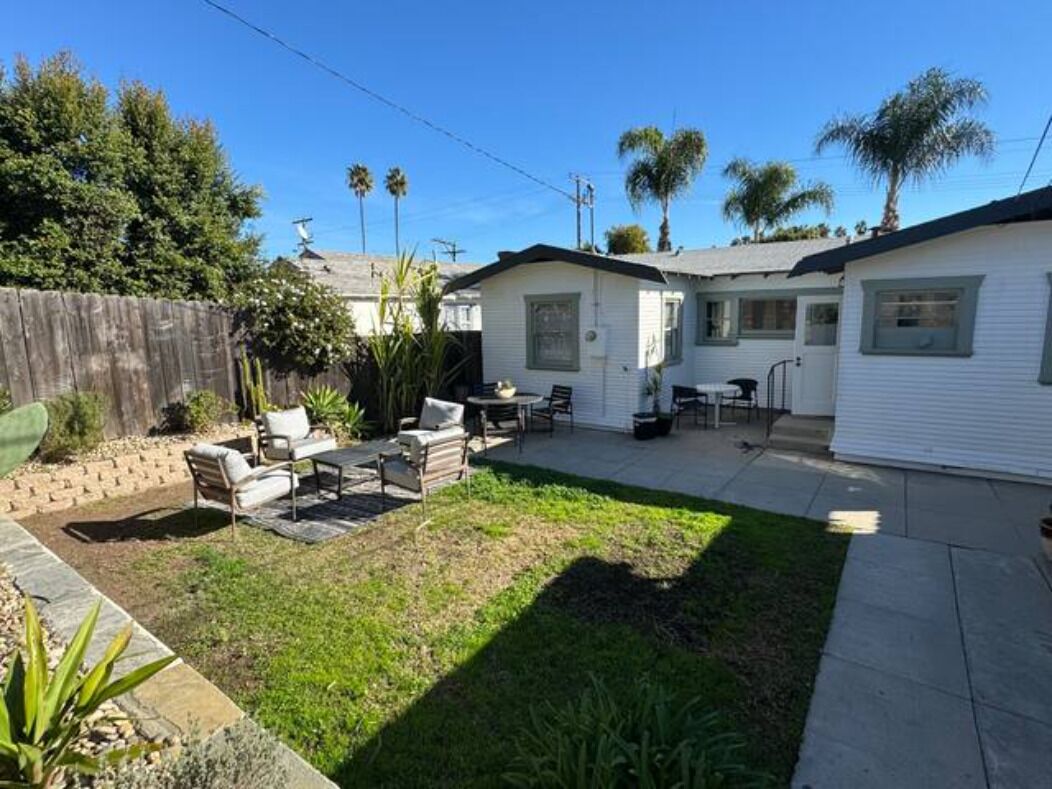 A residential property with a patio area, outdoor seating, and a fenced yard.