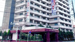 A multi-story hotel with a prominent entrance and signage indicating amenities. - Matsue Universalhotel   (Matsue)