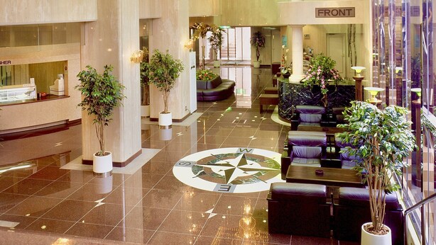 A spacious lobby with a large chandelier, seating areas, and a prominent compass floor design. - Matsue Universalhotel   (Matsue)