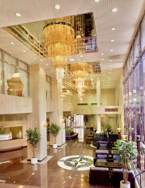 A spacious lobby with a large chandelier, seating areas, and a prominent compass floor design. - Matsue Universalhotel   (Matsue)