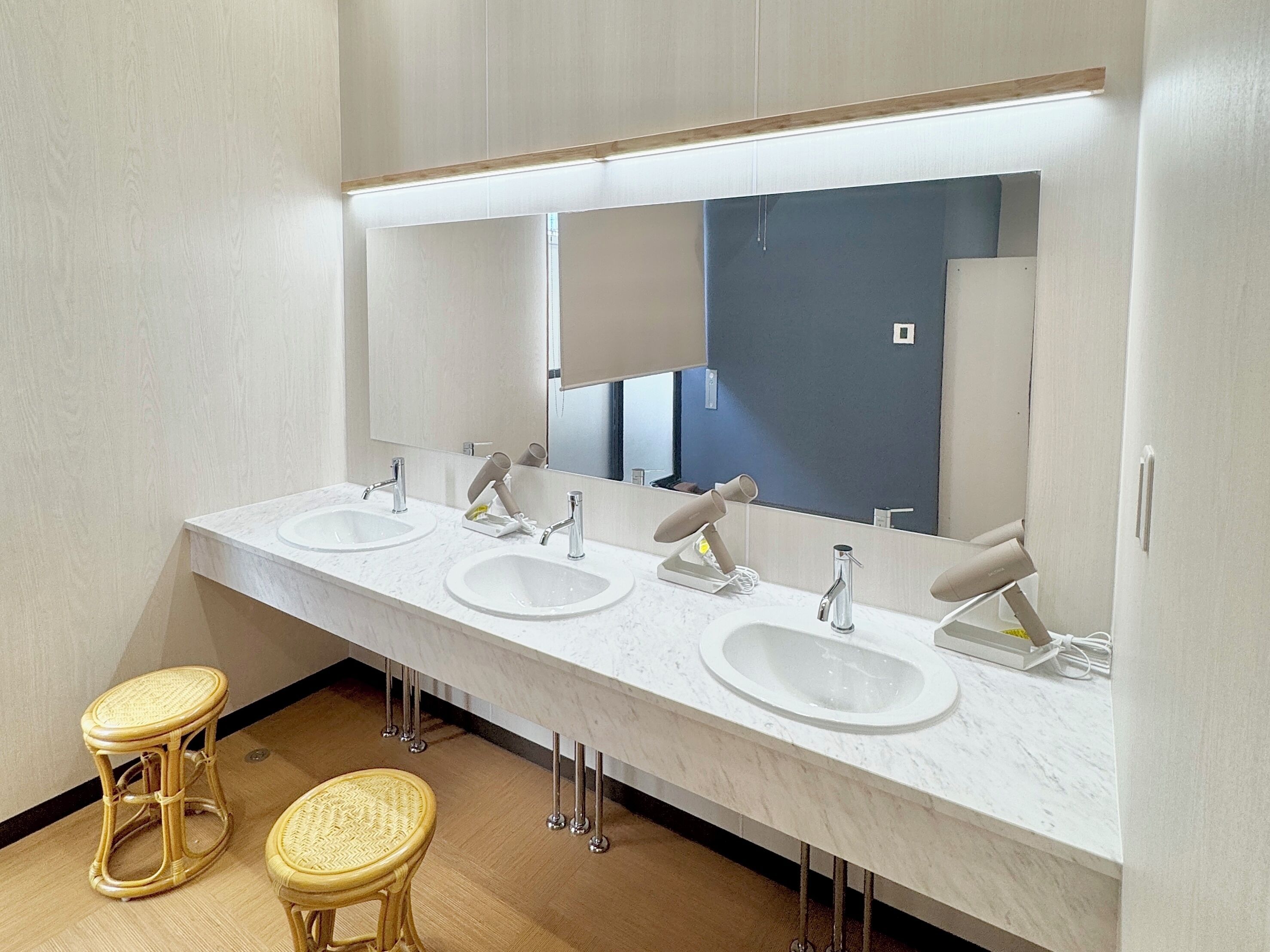 A modern bathroom with a long vanity, four sinks, and a large mirror.