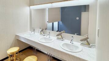 Une salle de bain moderne avec un long meuble-lavabo, quatre vasques et un grand miroir.
