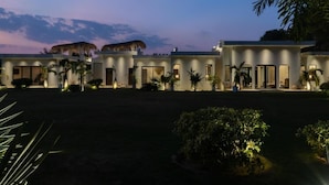 Um hotel moderno com vários edifícios interligados, com grandes janelas e uma entrada bem iluminada.