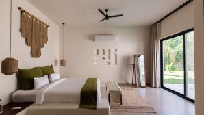 Quarto moderno com uma cama grande, ventilador de teto, ar condicionado e vista para o exterior através de uma janela ampla.