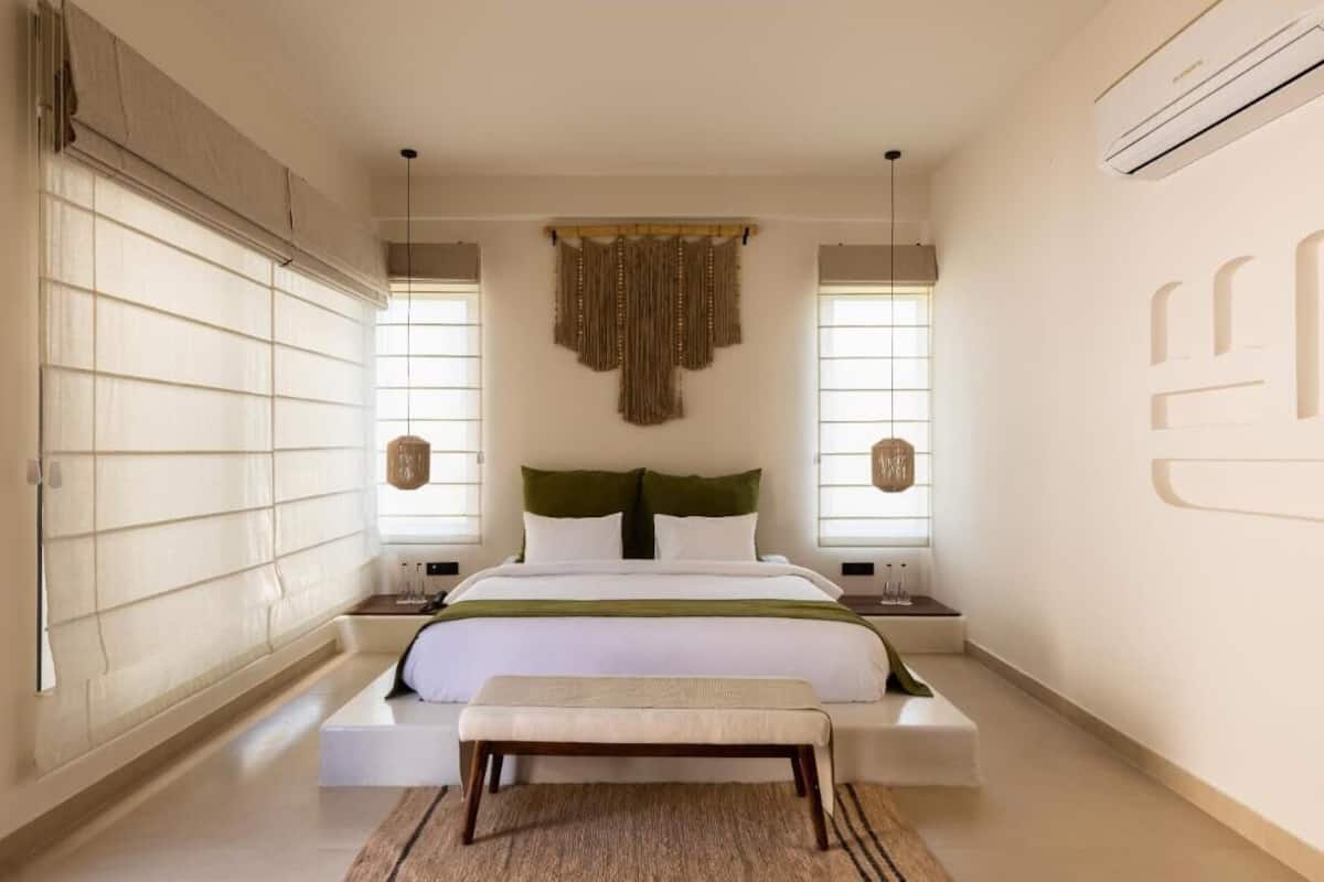 Een slaapkamer met een bed, een bankje en twee nachtkastjes.