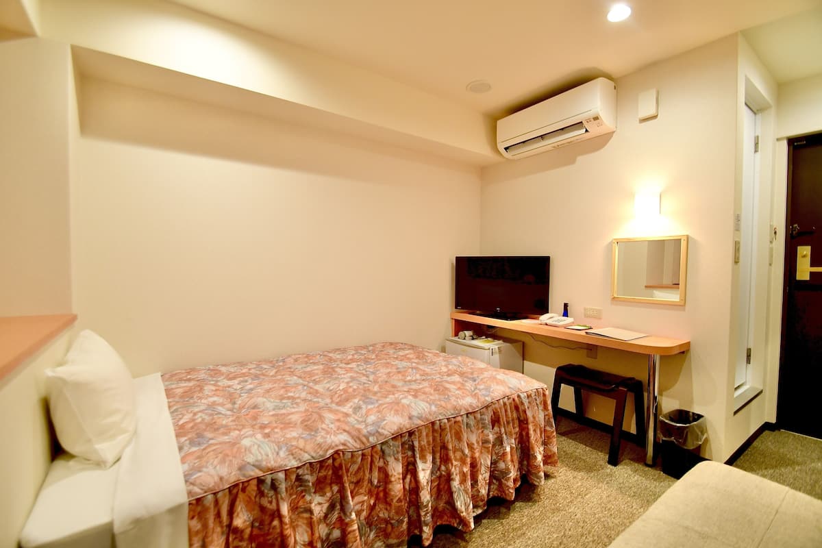 Een hotelkamer met een bed, bureau, stoel en een klein tafeltje.