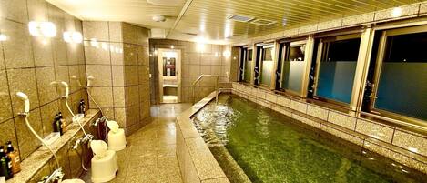 A hotel bathroom with a large bathtub, multiple sinks, and a glass-enclosed window.