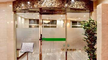 A hotel entrance with a marble reception desk, a green directional sign, and a no-smoking sign.