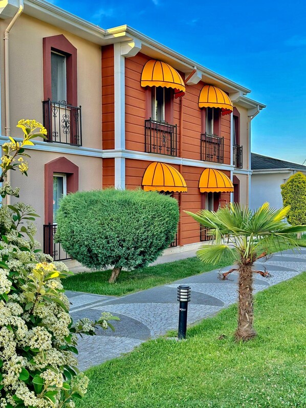 A multi-story hotel with balconies, a well-maintained lawn, and a clear sky. - SAPANCA RESORT HOTEL (Sapanca)