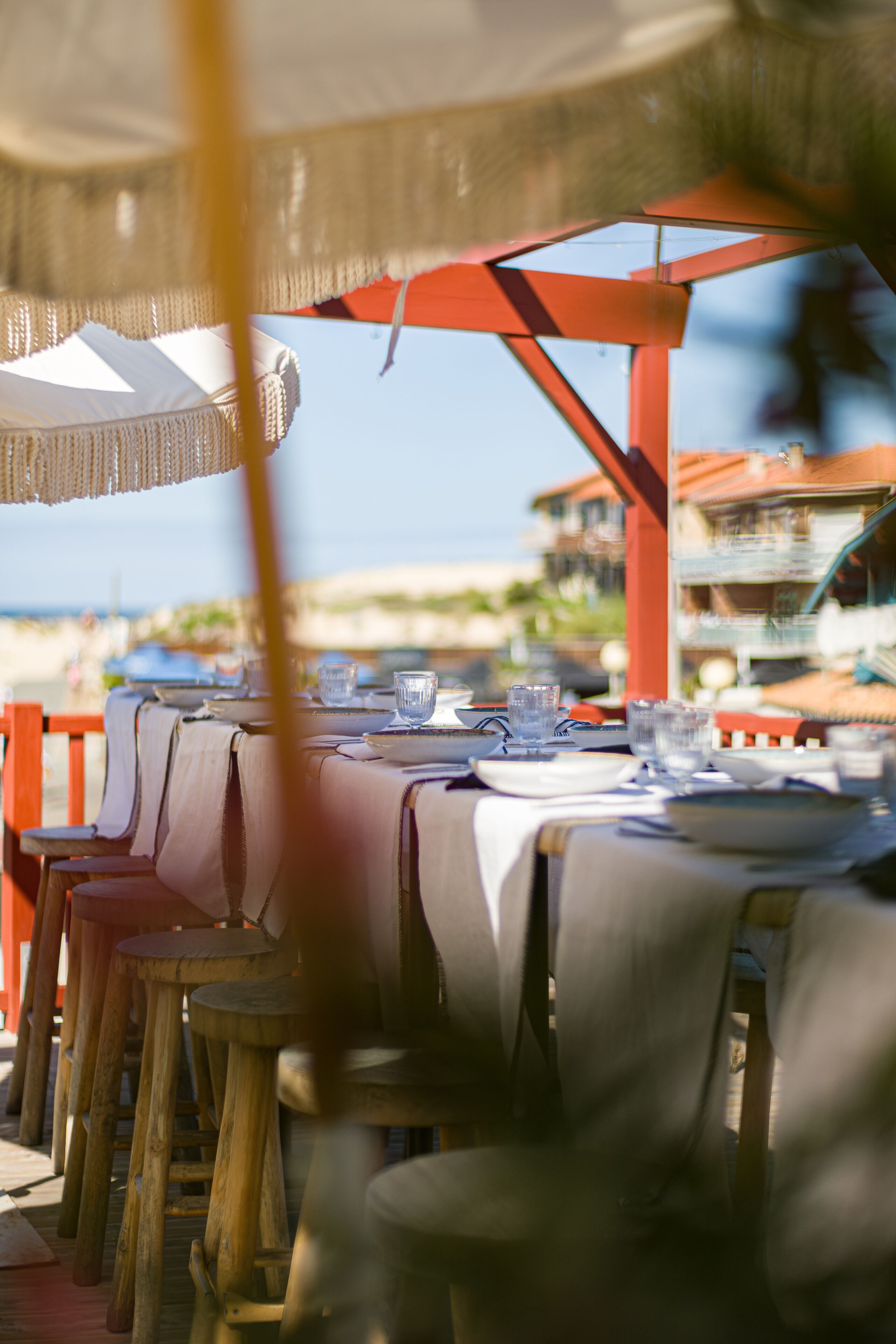 A seaside restaurant with tables set for dining, overlooking the beach.