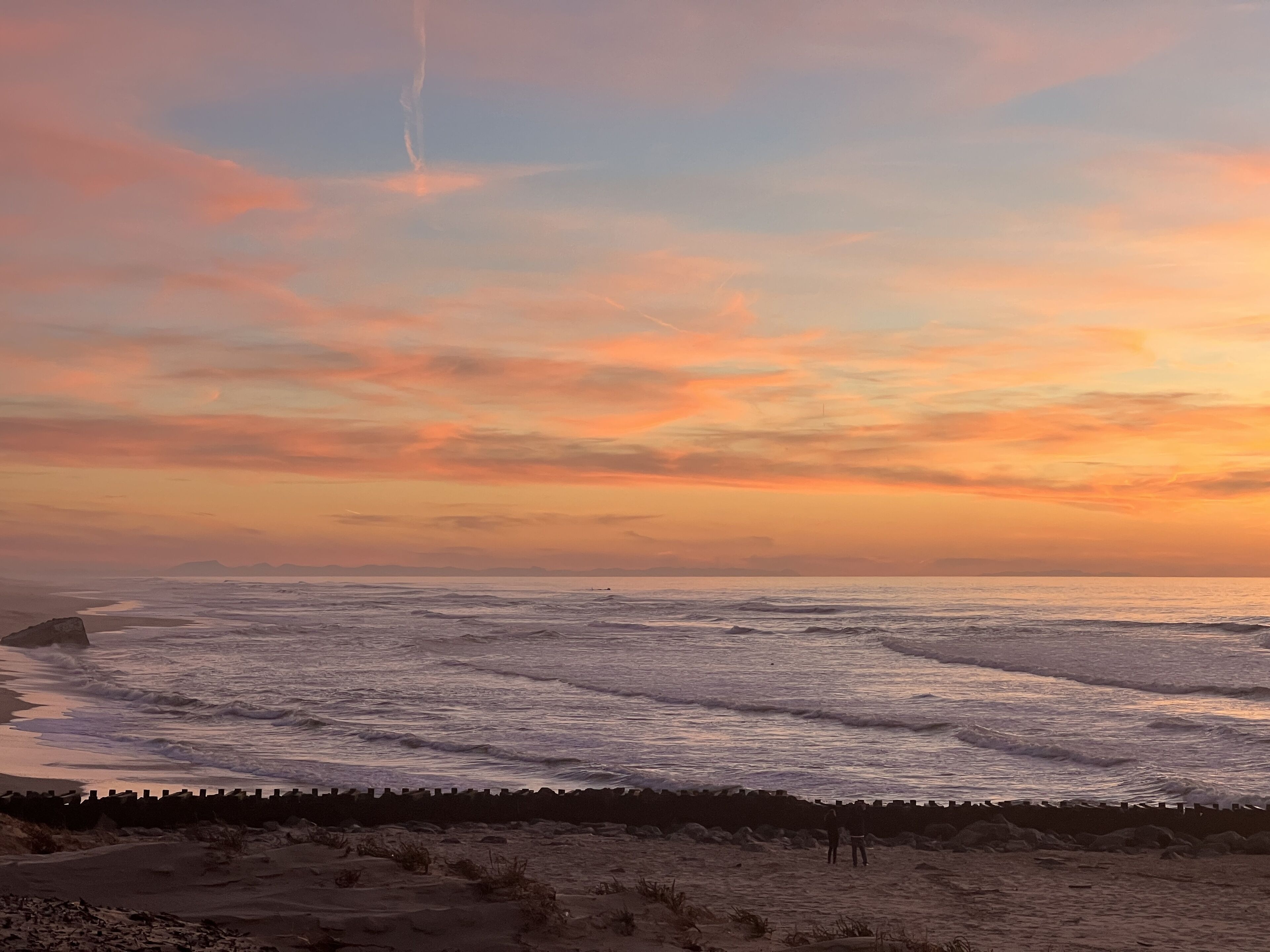 Een strand met golven en een zonsondergang.
