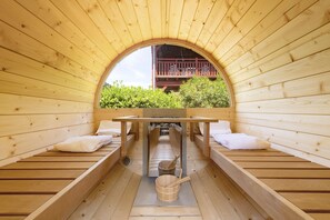 Een sauna met houten banken, een tafel en uitzicht op groen.