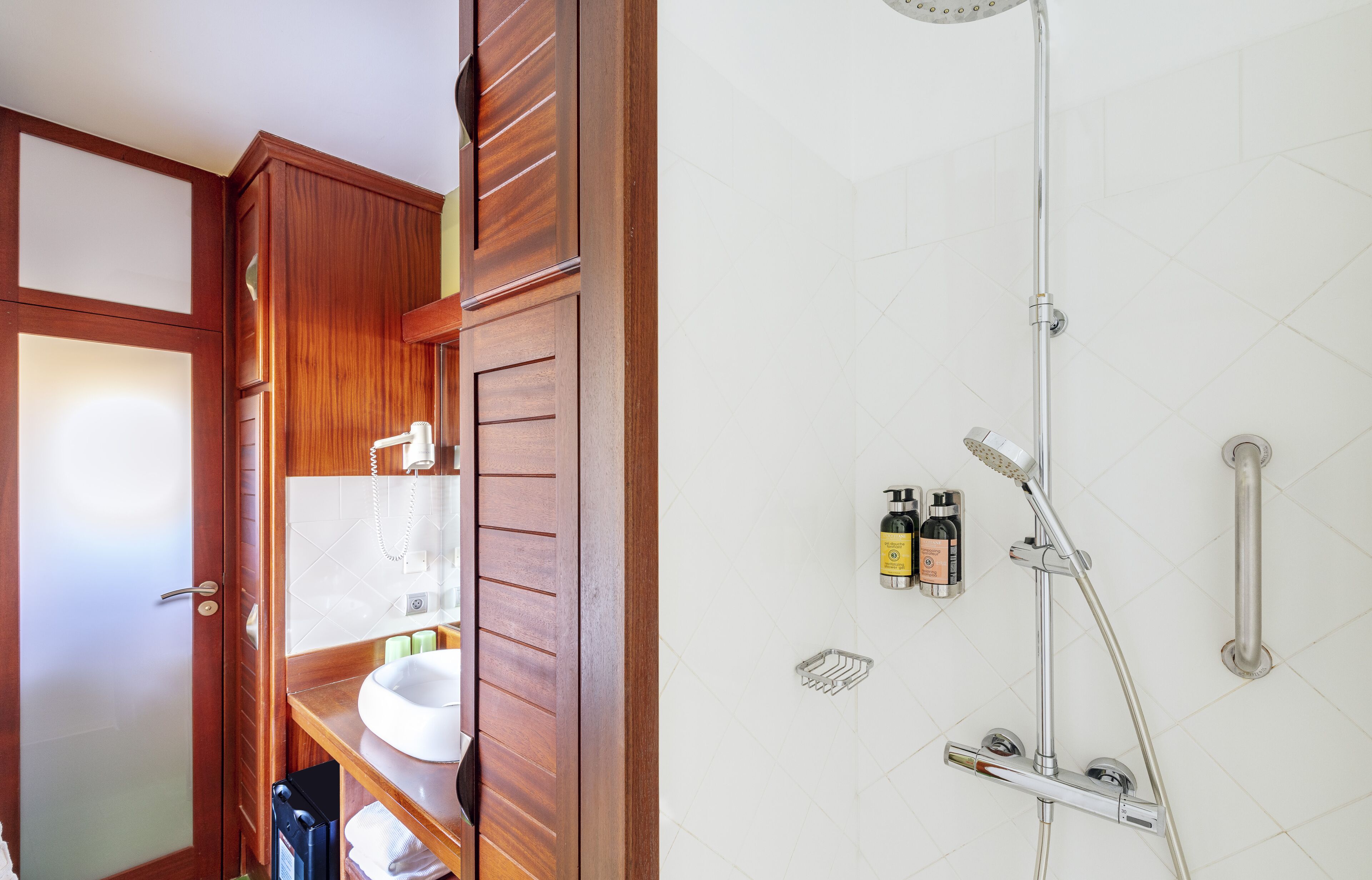 A bathroom with a wooden vanity, a sink, and a shower with a handheld showerhead.