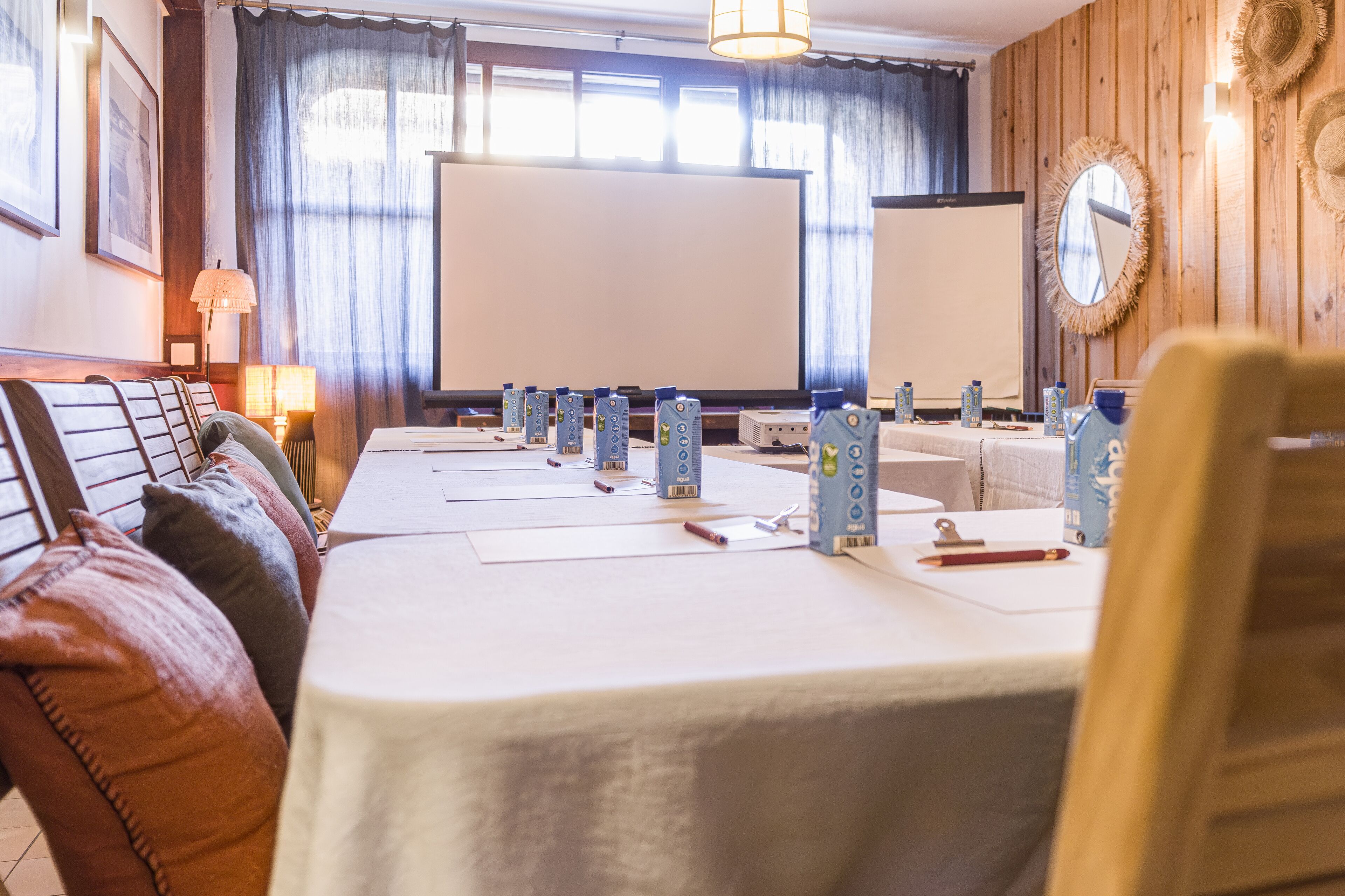 Uma sala de conferências com uma mesa comprida, cadeiras e uma tela de projeção.