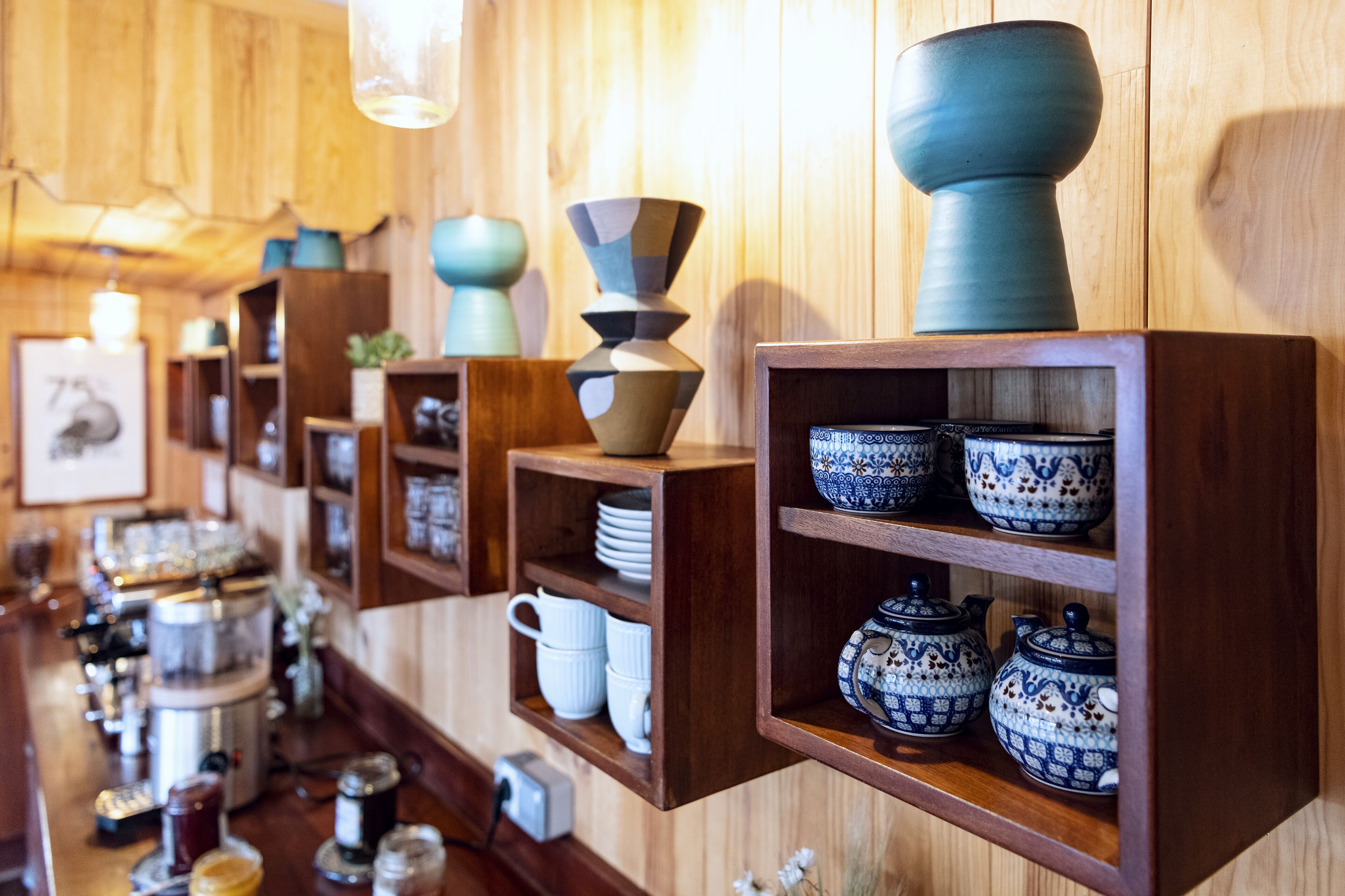 A display of ceramic bowls and teapots on wooden shelves in a shop.