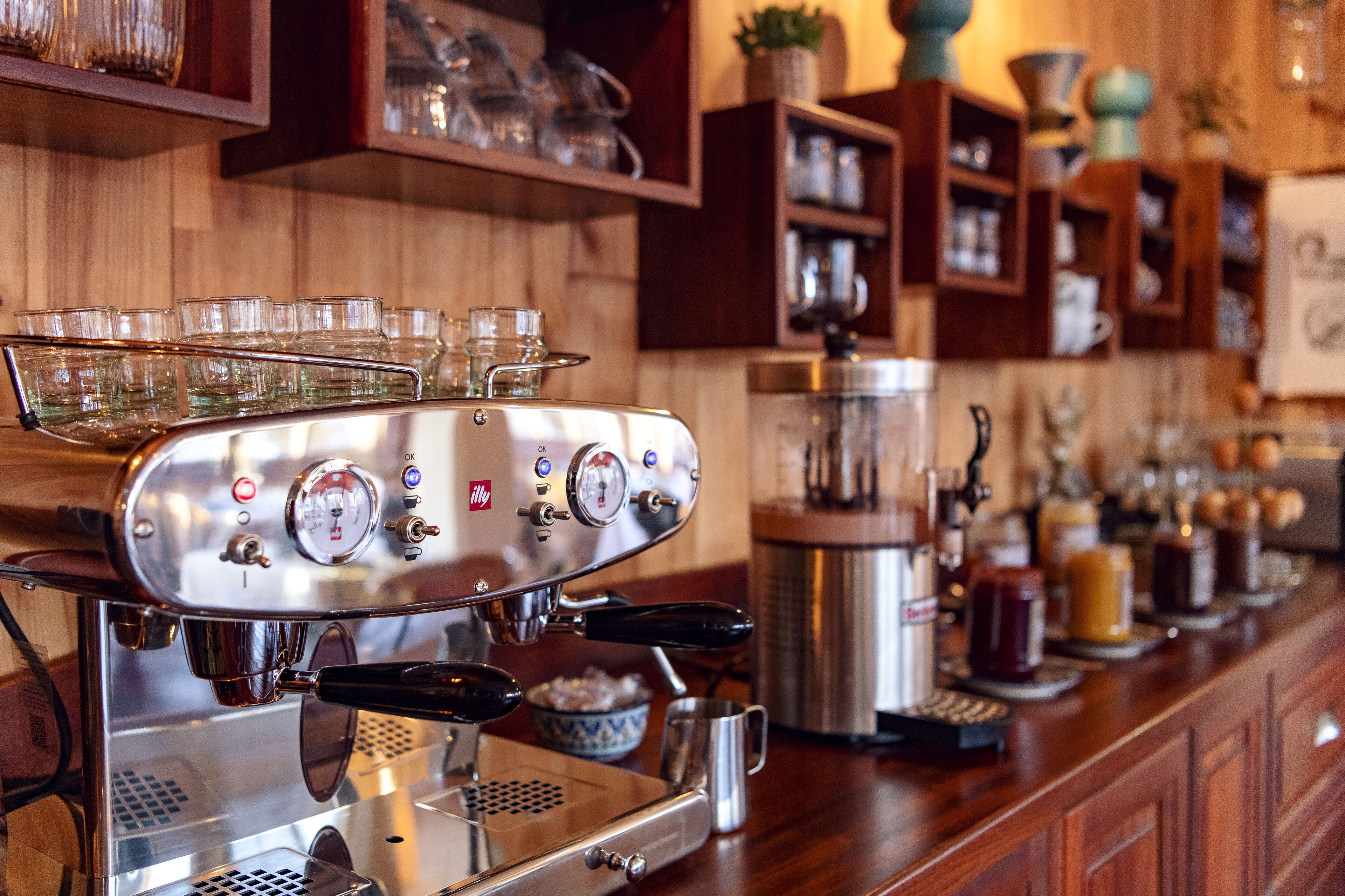 A coffee machine with multiple portafilters and a milk frothing station.