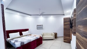 Une chambre à coucher comprenant un lit, un canapé, un ventilateur de plafond et un téléviseur fixé au mur.