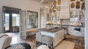 Una cocina amplia con una isla grande, vigas de madera en el techo y diversos paneles de madera colgantes.