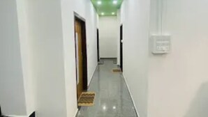 A narrow hallway with white walls, a green ceiling, and a shiny floor. - Kaziranga Inn (Bokakhat)
