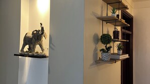 Ein Flur mit einer Leuchte, einem Regal mit einer Skulptur und einem Schrank mit Pflanzen und einem Buch mit dem Titel „Kelly Hoppen Style“.