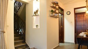 A staircase with a metal railing, a shelf with a decorative item, and a dining area with a table and chairs.