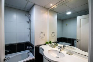 A modern bathroom with a bathtub, two sinks, a large mirror, and a shower. - Yogi - Marina Marvel Luxurious 1BR Apt at Al Shera Tower (Dubai)