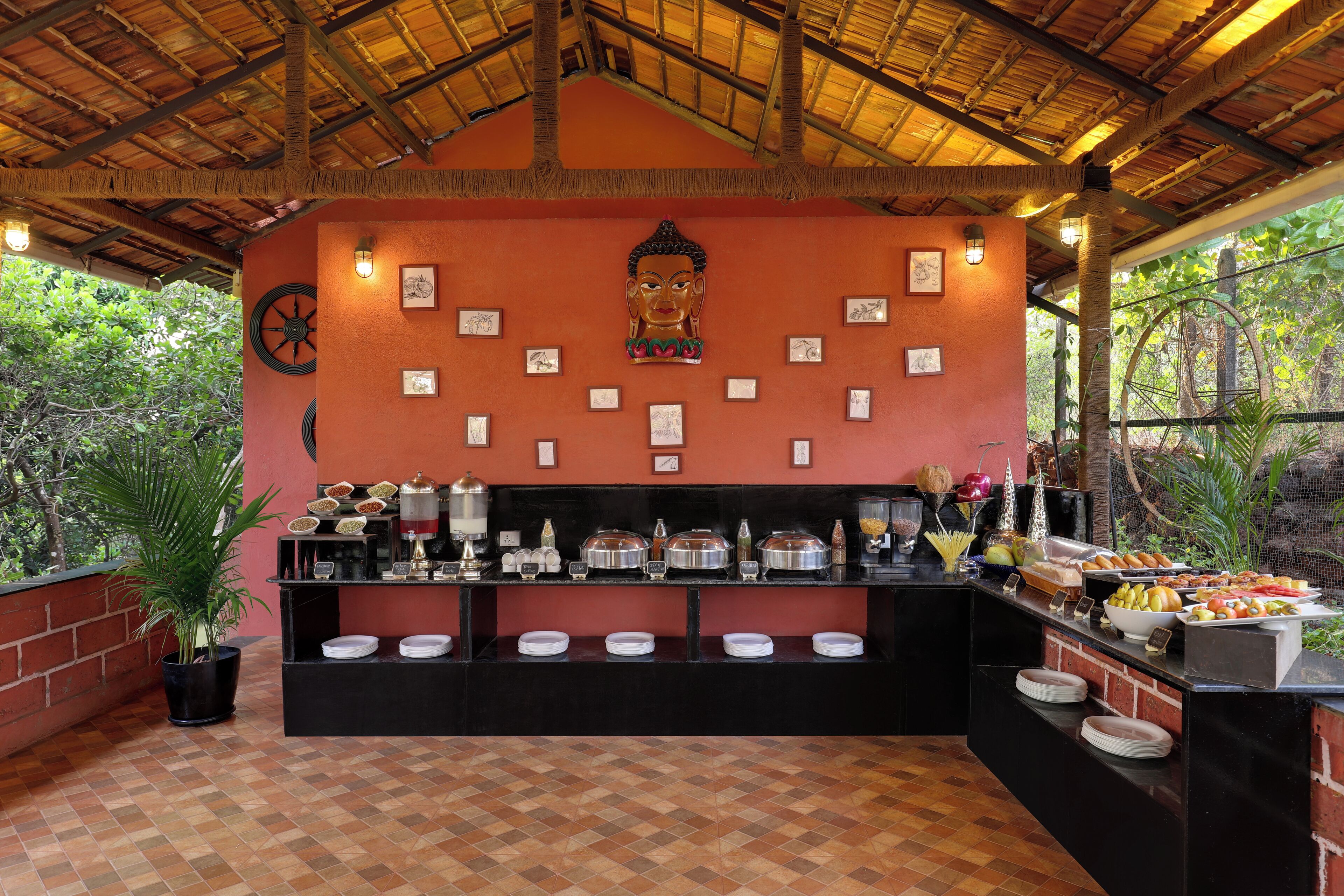 A buffet setup with food items and a Buddha statue on the wall.