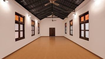 A long, narrow hallway with a high ceiling, multiple windows, and a central door.