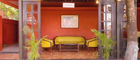 A reception area with a wooden bench, two chairs, a table, and a framed picture on the wall.