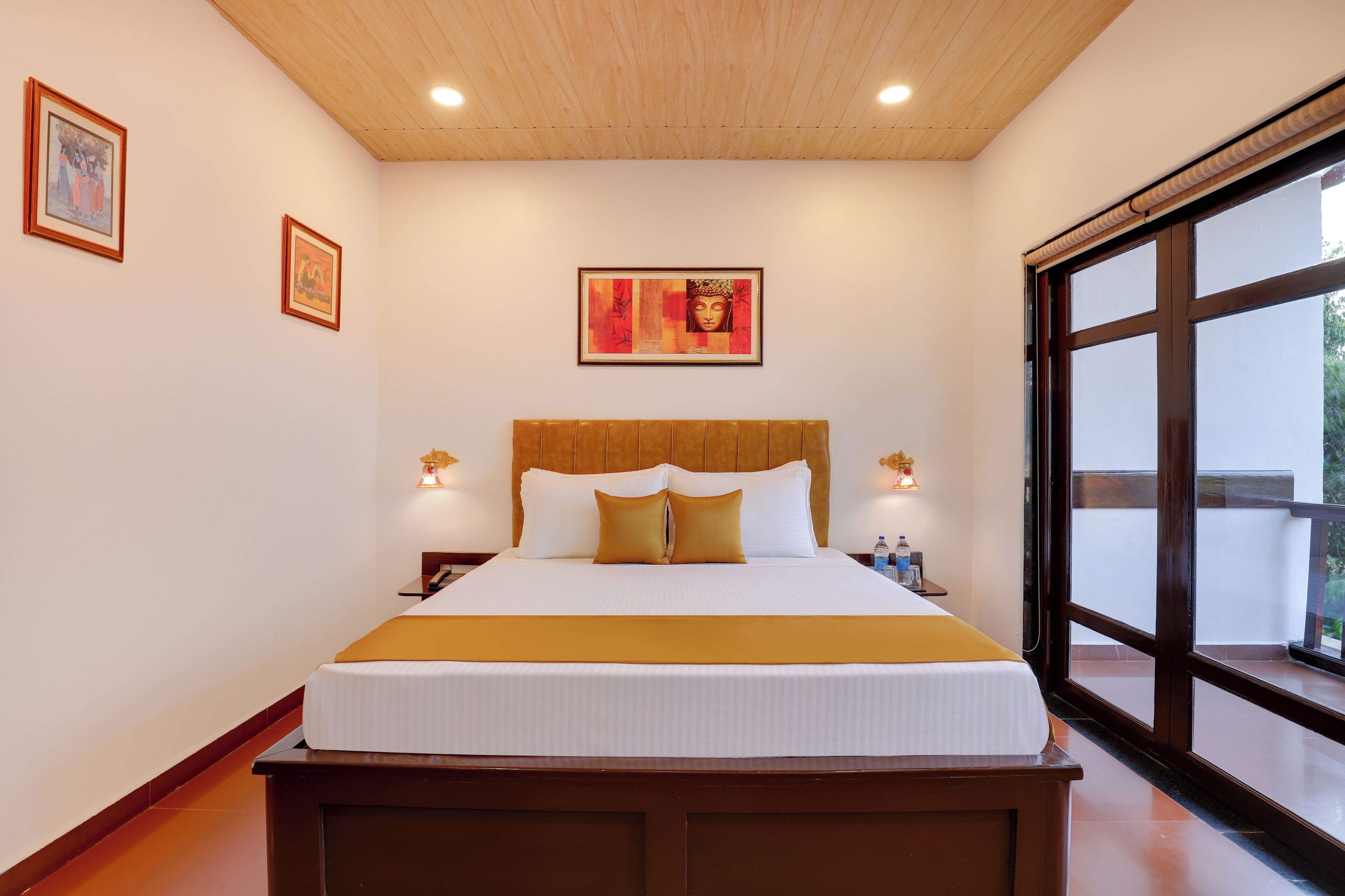 A large bed with a wooden headboard, two bedside tables with lamps, and a framed artwork above the bed.