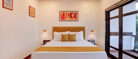 A large bed with a wooden headboard, two bedside tables with lamps, and a framed artwork above the bed.