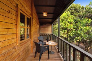 Una terraza de madera con una mesa y sillas, con vista a un jardín.