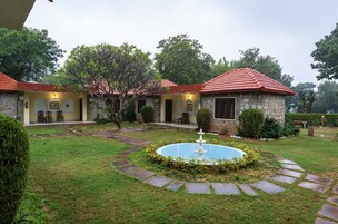 Un patio con piscina, edificios de piedra con techos rojos y un césped bien cuidado.
