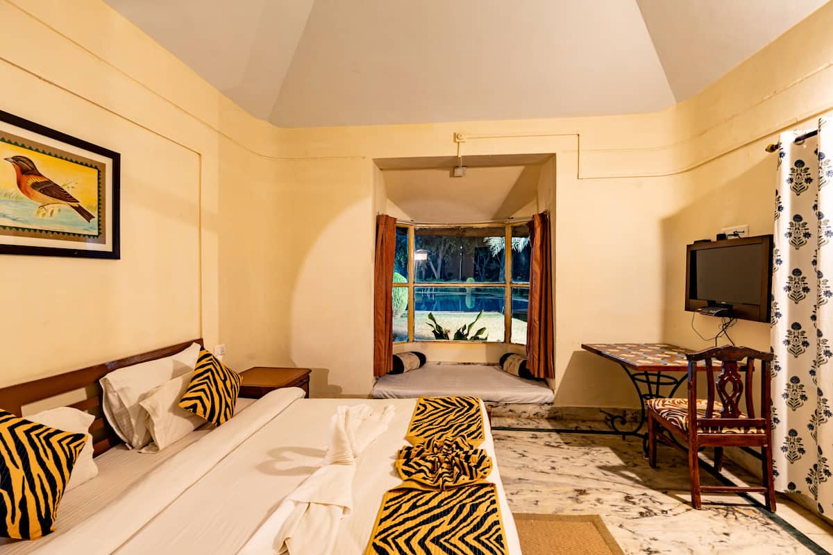 A hotel room with a bed, a desk, a television, and a window with curtains.