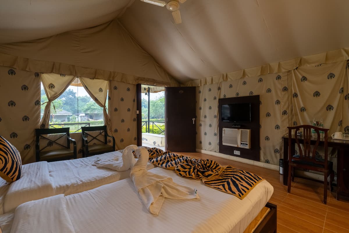 A tent-style room with two beds, a TV, and a view of the outdoors.