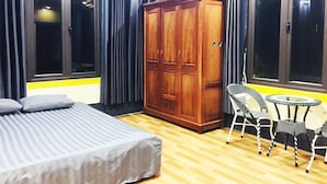A room with a bed, a wardrobe, a dining table with chairs, and large windows with curtains. - Scenic Views Farmstay & Hostel (Sa Pa)