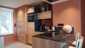 A modern kitchen with a central island, built-in oven, and a window providing natural light.
