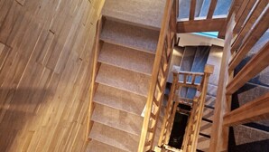 A wooden staircase with a handrail and a view of the upper floor.